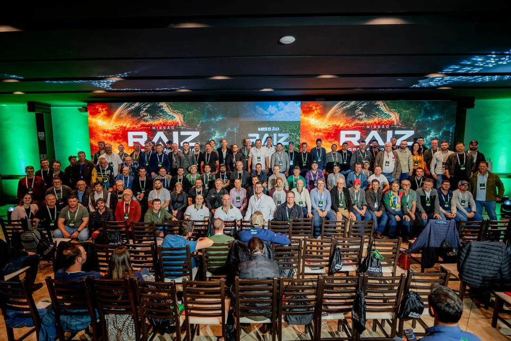 Foto de grupo dos participantes da Missão Raiz em Passo Fundo, diante do telão do evento